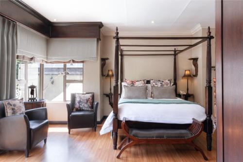 a bedroom with a canopy bed and two chairs at InnJoy Boutique Hotel in Centurion