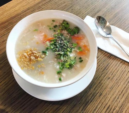 a bowl of soup on a table with a spoon at Pranot Apartment & Spa in Nonthaburi