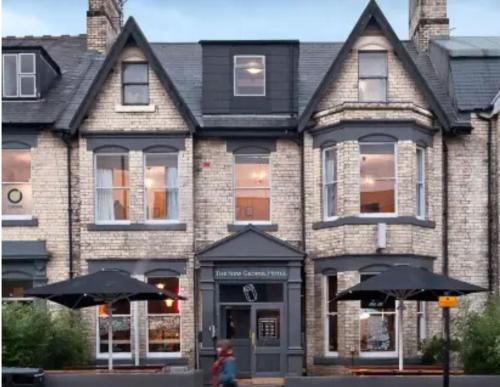 a large brick building with two umbrellas in front of it at The New George Hotel in Newcastle upon Tyne