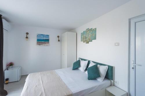 a white bedroom with a bed with green and white pillows at Vila Troia Vama Veche in Vama Veche
