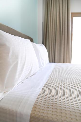 a white bed with white pillows and a window at Eumorphia Studios & Apartments in Skiathos Town