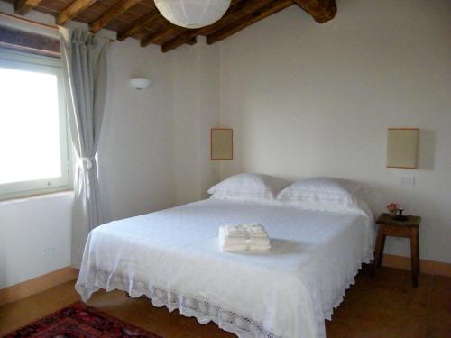 1 dormitorio con 1 cama con sábanas blancas y ventana en Holiday home Cielsereno, en Radicondoli