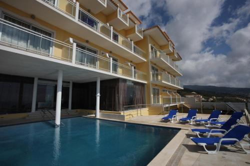 un hotel con piscina con sillas y un edificio en Hotel Apartamentos Baia Brava, en Gaula