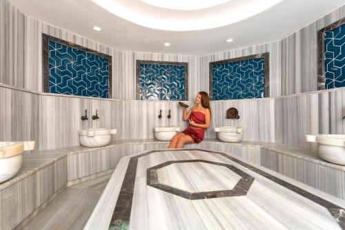 Una mujer en un baño con dos lavabos y una bañera en CHARM BEACH HOTEL, en Akyarlar