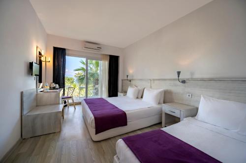 a hotel room with two beds and a window at CHARM BEACH HOTEL in Akyarlar