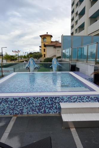a swimming pool with blue and white tiles in a building at Hotel Columbus in Lignano Sabbiadoro