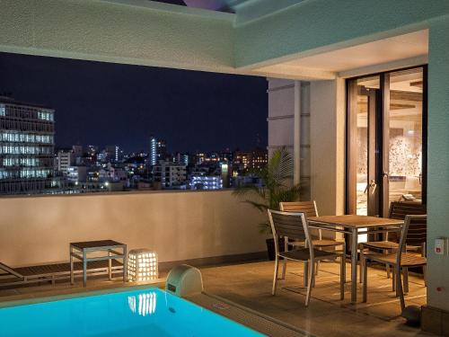 a balcony with a table and chairs and a view of the city at Okinawa EXES Naha in Naha
