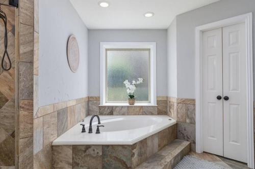 a bathroom with a bath tub and a window at Large Executive Family Home with Pool near DFW Airport in Keller