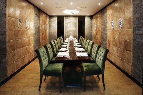a long dining room with a long table and green chairs at Savoy Hotel Myeongdong in Seoul