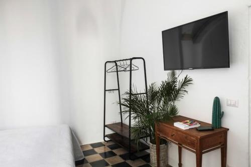 a bedroom with a tv and a table with a plant at CALMAPIANTA home for green lovers in Putignano