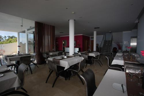 a restaurant with tables and chairs and a staircase at Hotel Apartamentos Baia Brava in Gaula