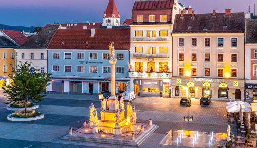 a city square with a fountain in front of buildings at Hotel Zentral in Wiener Neustadt
