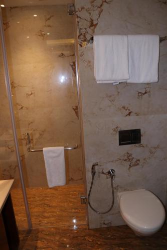 a bathroom with a shower with a toilet and towels at Regenta Inn Amristar Airport Road by Royal Orchid Hotels Limited in Amritsar