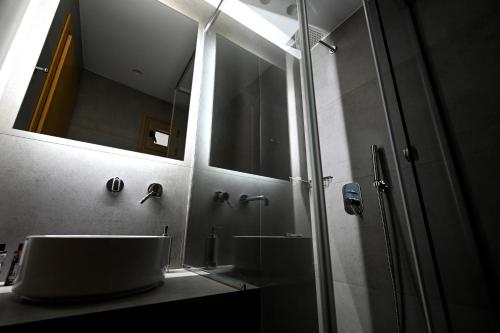 a bathroom with a sink and a shower with a mirror at Eumorphia Studios & Apartments in Skiathos Town