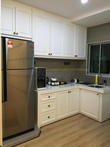 eine Küche mit weißen Schränken und einem Kühlschrank aus Edelstahl in der Unterkunft Pearl Rice Garden (European Style) in Sekinchan