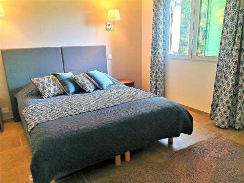 a bedroom with a bed with blue pillows and a window at Domaine de La Font des Pères - Teritoria in Le Beausset
