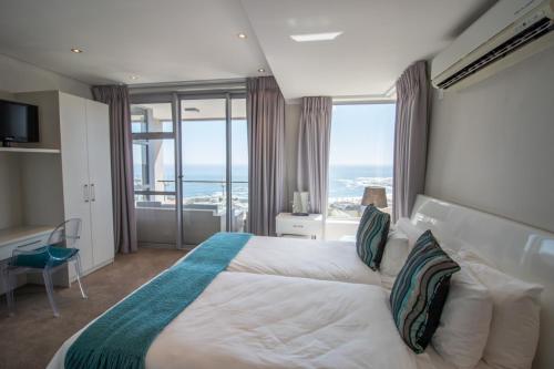 a bedroom with a bed with a view of the ocean at The Crystal Apartments in Cape Town