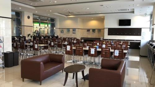 une grande chambre avec des chaises et des tables dans un bâtiment dans l'établissement Toyoko Inn Toyama-eki Shinkansen-guchi No.2, à Toyama