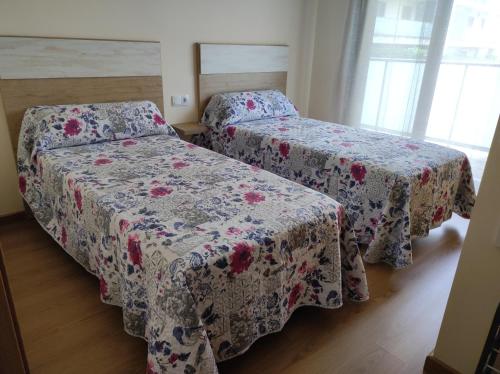two beds in a room with floral sheets at PINAR RESORT in Sant Jordi