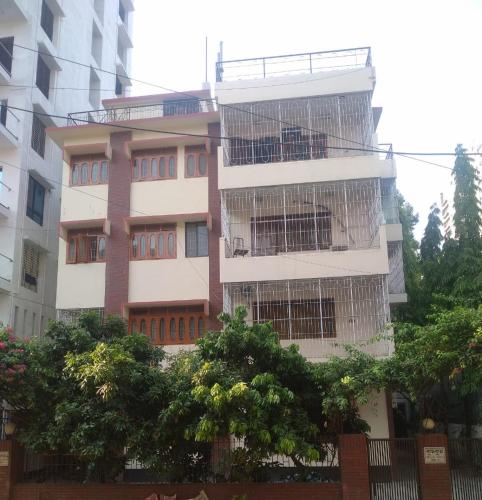 un grand bâtiment avec des arbres devant lui dans l'établissement Taz Garden House, à Dhaka