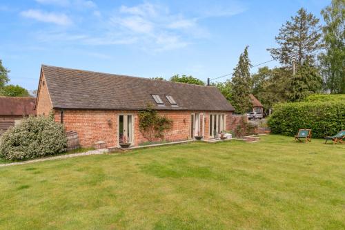 a red brick house with a large yard at The Barn at Kington Grange in Claverdon