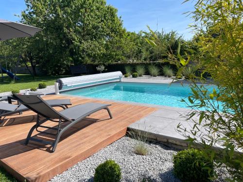 una piscina en un patio con mesa y sillas en LE BOIS DE MOINI- DOMAINE LOUE PAISIBLE - Calme-Terrasse-Parking- en Chouzelot
