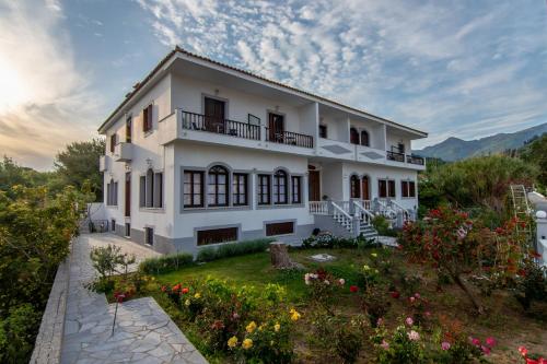 a white house with a garden in front of it at Iro's Residence in Ágios Konstantínos
