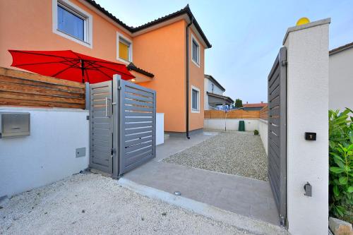 a house with an open gate with a red umbrella at Villa with private pool in village Jadreški in Pula