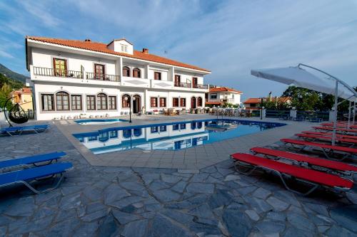 a building with a pool and some red and blue chairs at Iro's Residence in Ágios Konstantínos