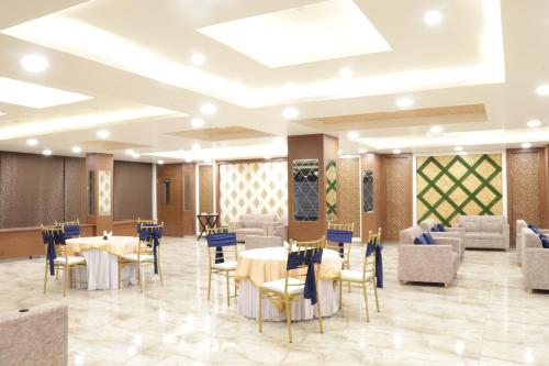 ein Restaurant mit Tischen und Stühlen in einem Zimmer in der Unterkunft Hotel Royal Palm Dehradun in Dehradun