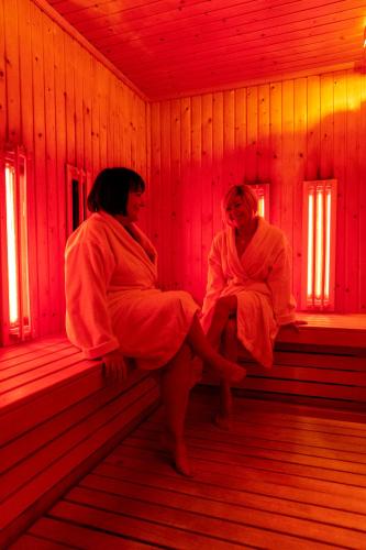 two women sitting on benches in a red room at Hotel Mistral Sport in Gniewino