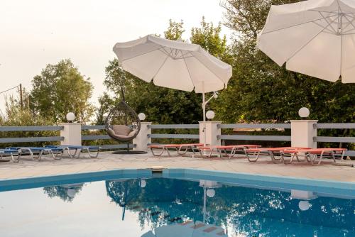 a pool with two umbrellas and tables and chairs next to at Iro's Residence in Ágios Konstantínos