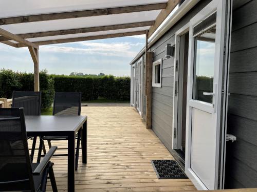 d'une terrasse avec une table, des chaises et une porte. dans l'établissement Polderhuisje 2 - Heerlijk chalet met overkapt terras en 2 slaapkamers - max 4 pers - 3 km van Noordzee - locatie op camping 2, à Rockanje