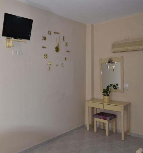 a room with a clock on the wall and a table at Vardes Hotel Studios in Amoopi