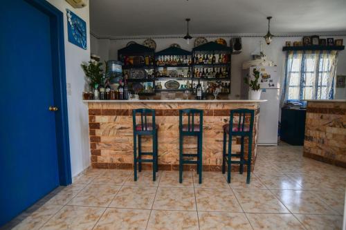 a kitchen with a bar with two stools at Vardes Hotel Studios in Amoopi