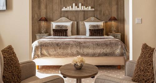 a bedroom with a bed and two chairs and a table at Victor's Seehotel Weingärtner Bostalsee in Bosen-Eckelhausen