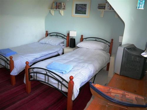 Habitación con 2 camas individuales y TV. en Bar Hill Lodge en Gatehouse of Fleet