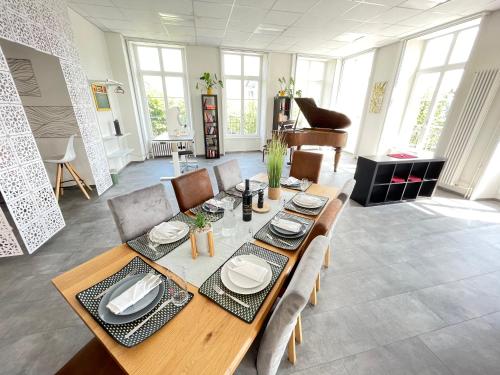 a dining room with a table and a piano at The 5 Continents I & II - 320 m2 by Stay Swiss in Porrentruy