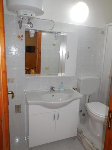 a bathroom with a sink and a toilet and a mirror at Apartment Roasi in Trapani