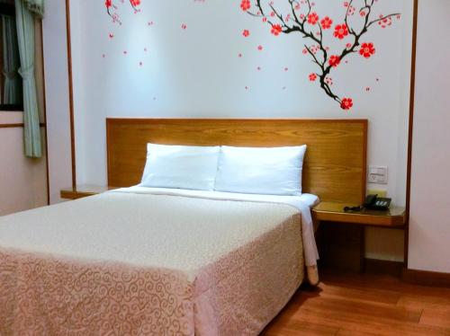 a bedroom with a bed and a tree with red flowers on the wall at 東京大飯店 in Jiaoxi