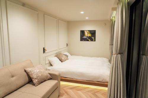 um pequeno quarto com uma cama e um sofá em ReTreat佐渡風島 グランピング- Self Check-In Only em Sado