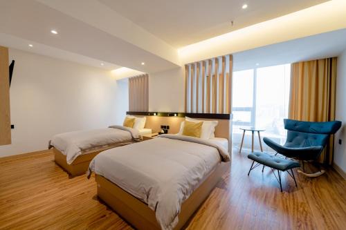 um quarto com 2 camas, uma secretária e uma cadeira em MIllennium Plaza Hotel & Mall Ulaanbaatar em Ulan Bator