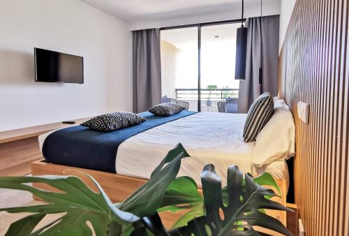 Aparthotel Bahia Pollensa في بورت دي بوينسا: غرفة نوم فيها سرير وامامها زرع