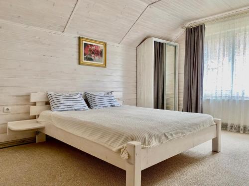 a bedroom with a large white bed with a window at Chalet Зоряні ночі in Mykulychyn