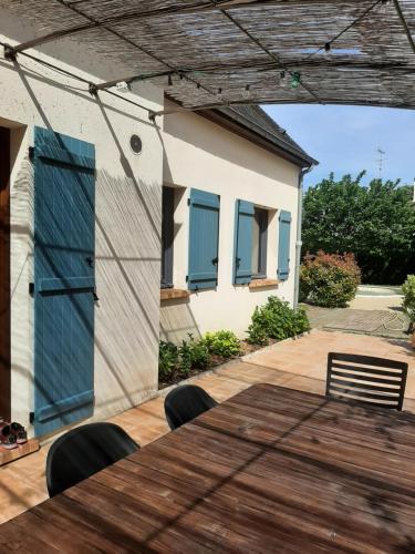 a house with a wooden table and a house with blue windows at Au Chat Perché chambre double in Mareil-sur-Mauldre