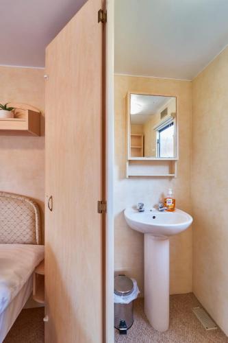 a bathroom with a sink and a mirror and a bed at Domek Duna1 Polanica Zdroj in Polanica-Zdrój