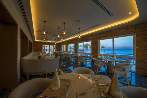 a restaurant with tables and chairs and a view of the ocean at Luxotel Aqaba Beach Resort & Spa Only 15 years plus in Aqaba