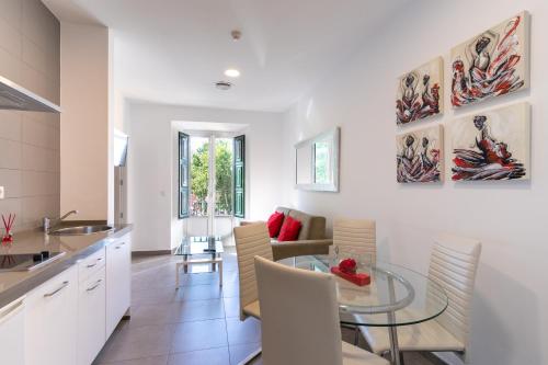 una cucina e una sala da pranzo con tavolo e sedie in vetro di Reservaloen Terrazas de la Catedral a Siviglia