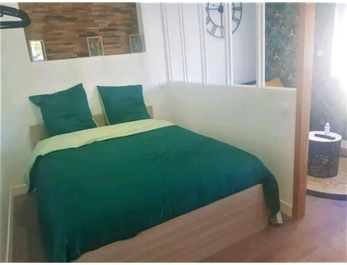 - un lit avec une couverture verte et des oreillers dans l'établissement La Nouvelle-Orléans - hyper-centre- 2mn SNCF - Wi-Fi Netflix gratuit, à Niort