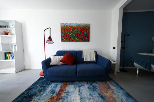 un sofá azul en una sala de estar con una pintura en Domus Silvana Apartments, en Rávena